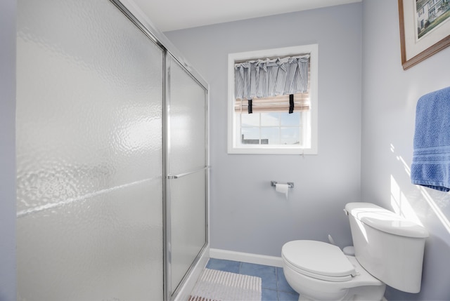 bathroom featuring tile patterned flooring, toilet, and a shower with shower door