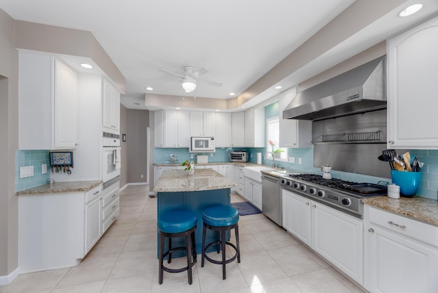 kitchen featuring stainless steel appliances, white cabinetry, and wall chimney exhaust hood