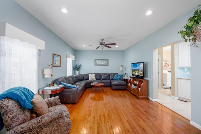 living room with washer / clothes dryer, light hardwood / wood-style flooring, and ceiling fan