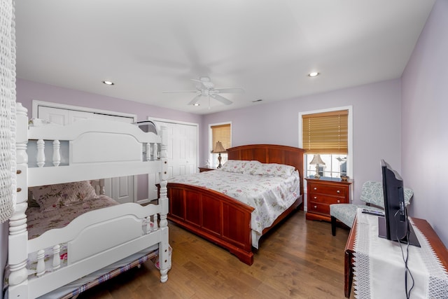 bedroom with dark hardwood / wood-style flooring, two closets, and ceiling fan