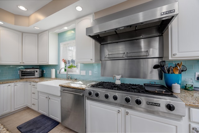 kitchen with white cabinets, appliances with stainless steel finishes, and wall chimney range hood