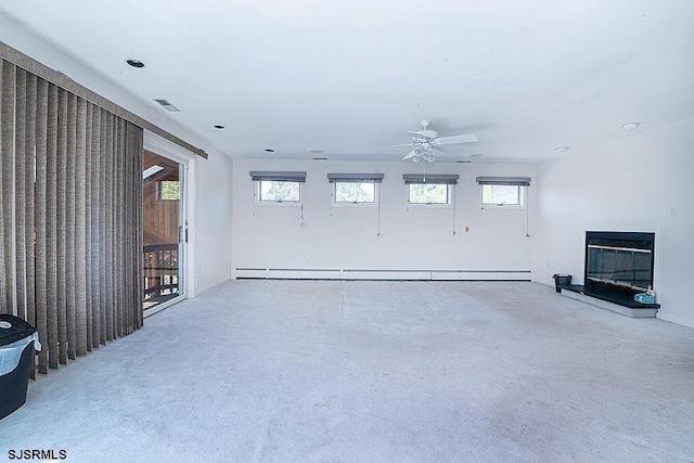 unfurnished living room featuring ceiling fan, a healthy amount of sunlight, light carpet, and a baseboard heating unit