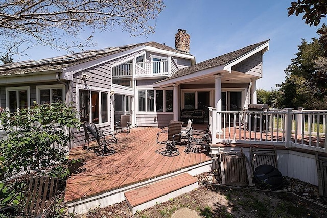 rear view of house featuring a balcony and a deck