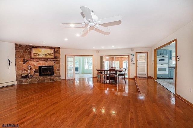 unfurnished living room with hardwood / wood-style flooring, ceiling fan, and a fireplace