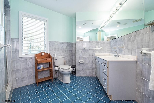 bathroom with tile patterned floors, walk in shower, vanity, tile walls, and toilet