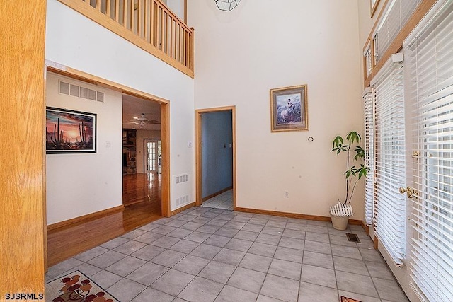 foyer entrance featuring light tile patterned floors, a healthy amount of sunlight, and a high ceiling