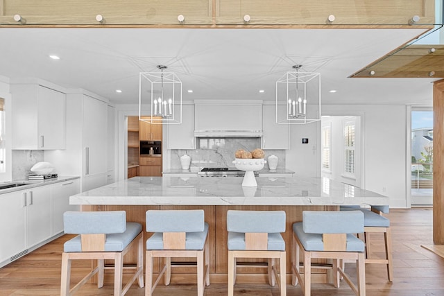 kitchen featuring backsplash, light stone counters, hanging light fixtures, and a spacious island