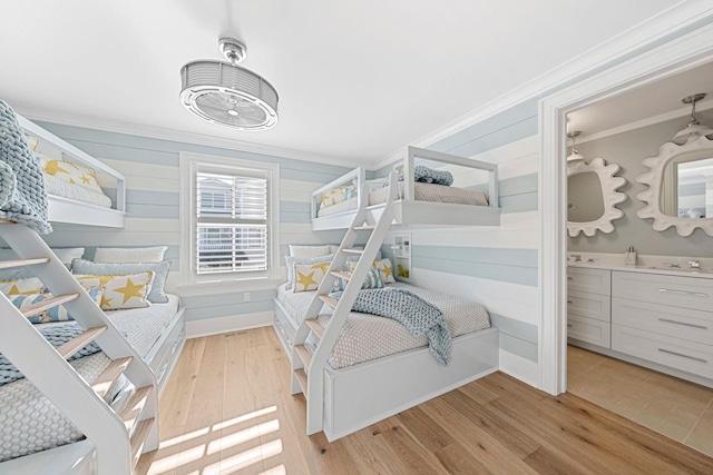 bedroom with wooden walls, light hardwood / wood-style flooring, and ornamental molding