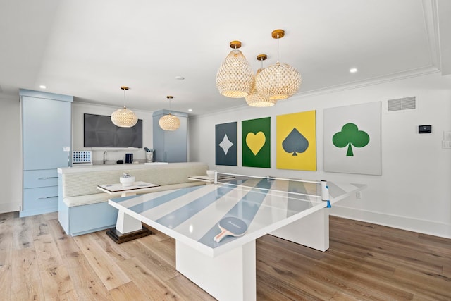 kitchen with pendant lighting, a large island, light wood-type flooring, and crown molding