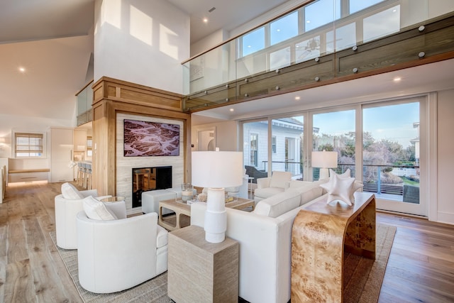 living room with a high ceiling, light hardwood / wood-style flooring, and a premium fireplace