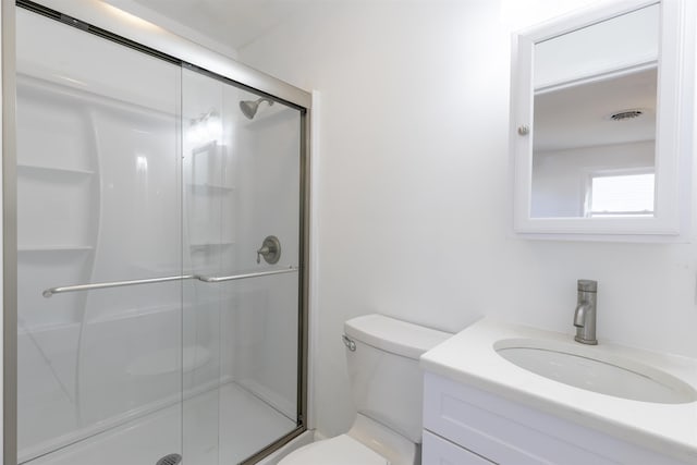 bathroom featuring a shower with door, vanity, and toilet