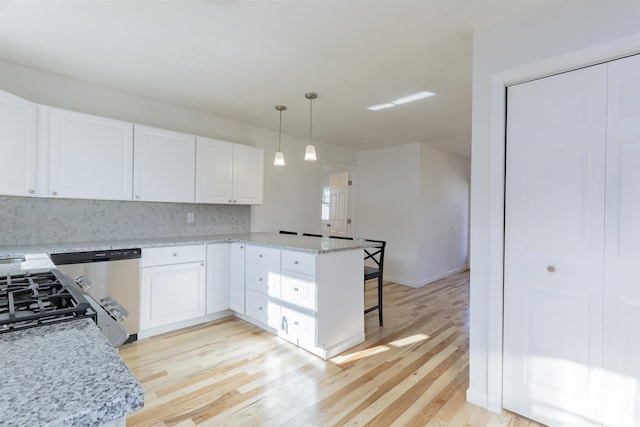 kitchen with kitchen peninsula, light stone countertops, light wood-type flooring, decorative light fixtures, and white cabinetry