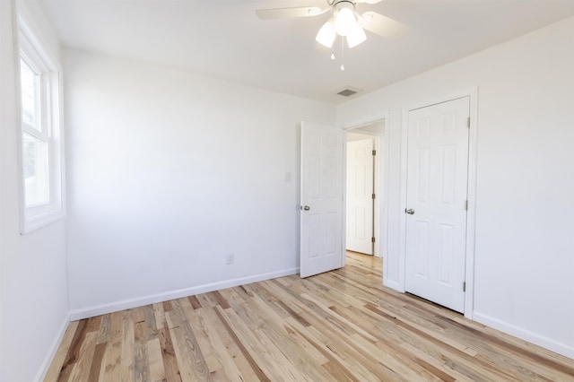 unfurnished bedroom with multiple windows, ceiling fan, and light hardwood / wood-style floors