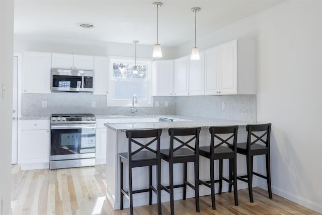 kitchen featuring kitchen peninsula, stainless steel appliances, and white cabinetry