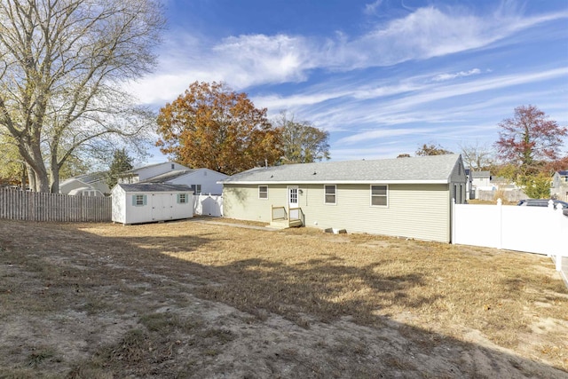 back of house with a storage shed