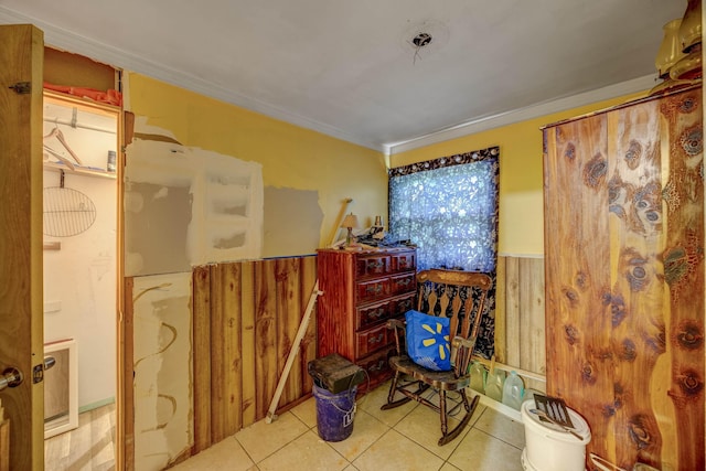 interior space featuring crown molding, light tile patterned flooring, and wood walls