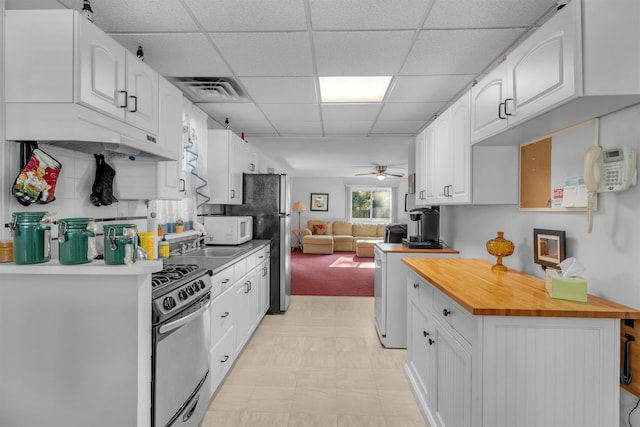 kitchen featuring ceiling fan, a drop ceiling, white cabinets, and stainless steel appliances