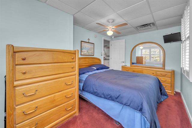 carpeted bedroom with ceiling fan and a drop ceiling