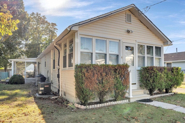 bungalow-style house featuring central air condition unit and a front yard