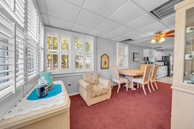 interior space with a paneled ceiling, ceiling fan, and carpet floors