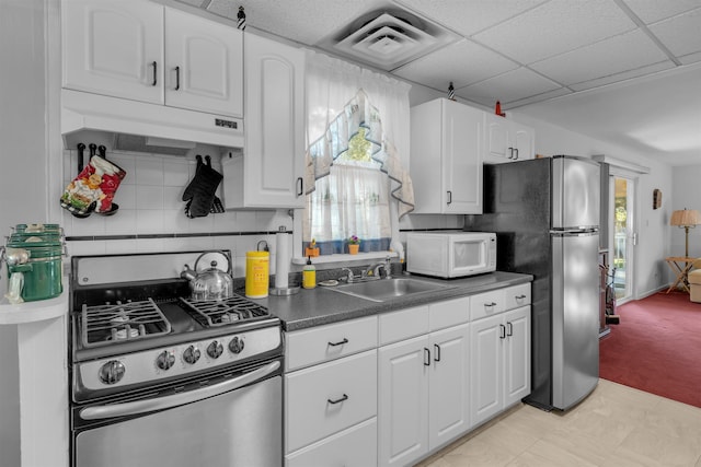 kitchen featuring white cabinetry, sink, a drop ceiling, light colored carpet, and appliances with stainless steel finishes