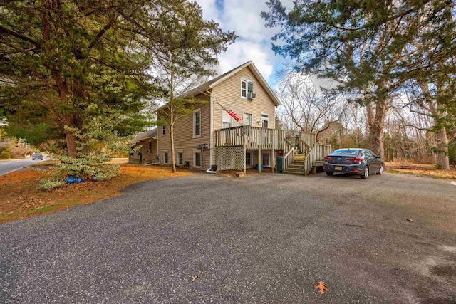 view of front of property featuring stairs, aphalt driveway, and a deck