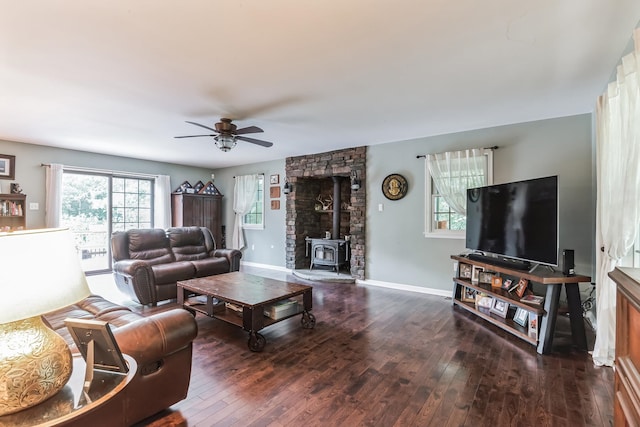 living room with a wood stove, ceiling fan, and dark wood-type flooring