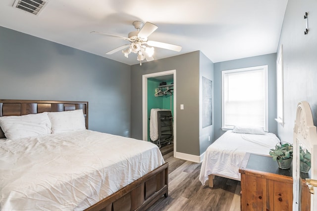 bedroom with a closet, a walk in closet, hardwood / wood-style flooring, and ceiling fan