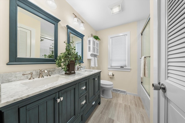 full bathroom featuring vanity, enclosed tub / shower combo, and toilet