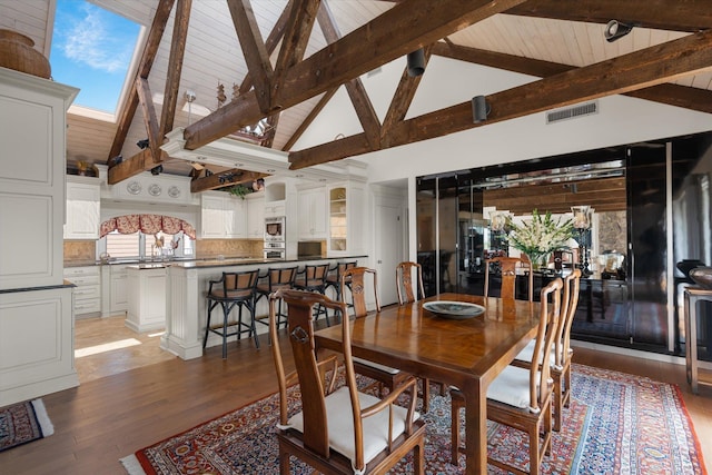 dining room featuring beamed ceiling, wood-type flooring, high vaulted ceiling, and a wealth of natural light