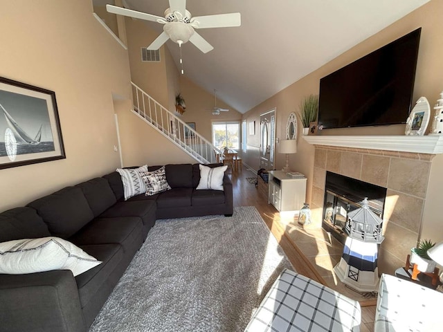 living room with ceiling fan, wood-type flooring, a fireplace, and high vaulted ceiling