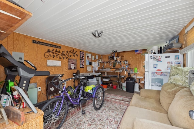 garage with freestanding refrigerator, wooden walls, a workshop area, and wooden ceiling