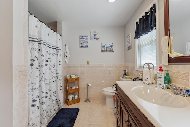 full bathroom featuring tile walls, tile patterned flooring, toilet, vanity, and a wainscoted wall