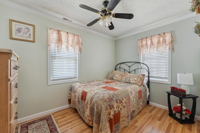bedroom with light wood-type flooring, ornamental molding, a textured ceiling, baseboards, and a ceiling fan