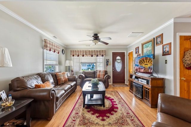 living area with crown molding, light wood-style flooring, and a ceiling fan
