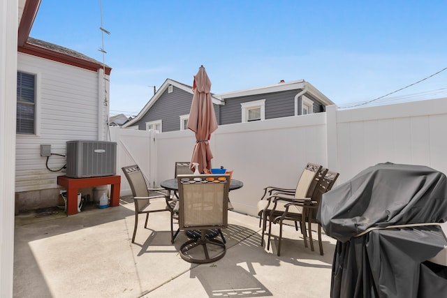 view of patio with outdoor dining space, central AC unit, a gate, and a grill