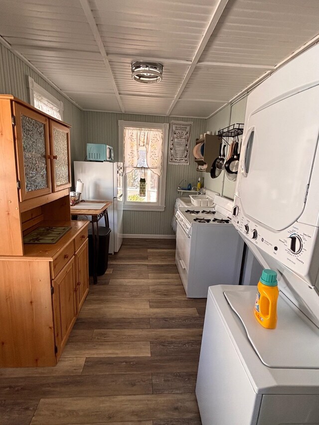 laundry area with baseboards, dark wood-type flooring, laundry area, and stacked washing maching and dryer