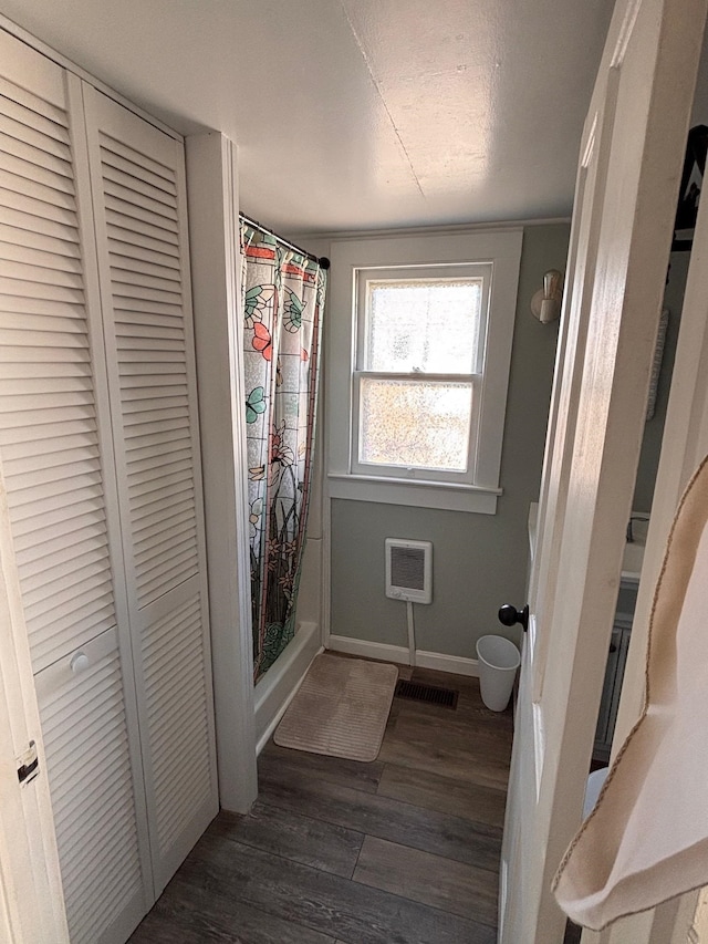 bathroom with a closet, a shower with shower curtain, baseboards, and wood finished floors