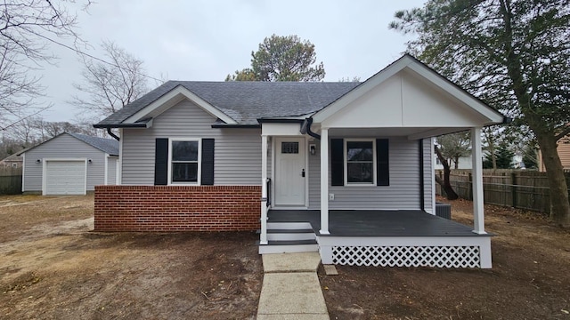 bungalow featuring an outbuilding, fence, roof with shingles, a garage, and brick siding