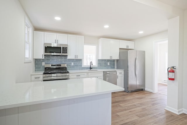 kitchen featuring stainless steel appliances, a sink, light countertops, and light wood-style floors