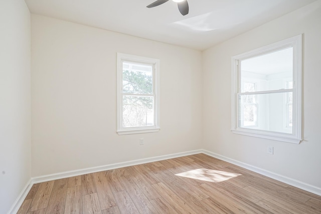 spare room with light wood-type flooring, a ceiling fan, and baseboards