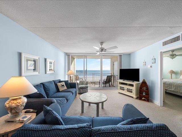 living room featuring a textured ceiling, a wall of windows, carpet, and ceiling fan