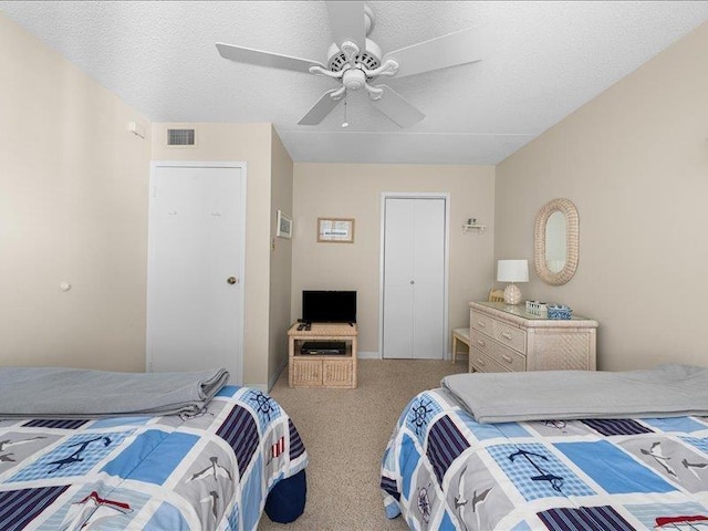 carpeted bedroom with ceiling fan, a closet, and a textured ceiling