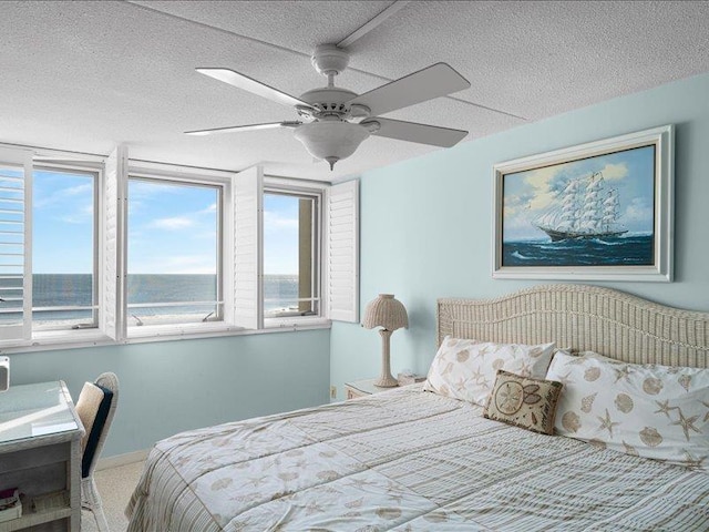 bedroom with carpet flooring, a textured ceiling, ceiling fan, and a water view