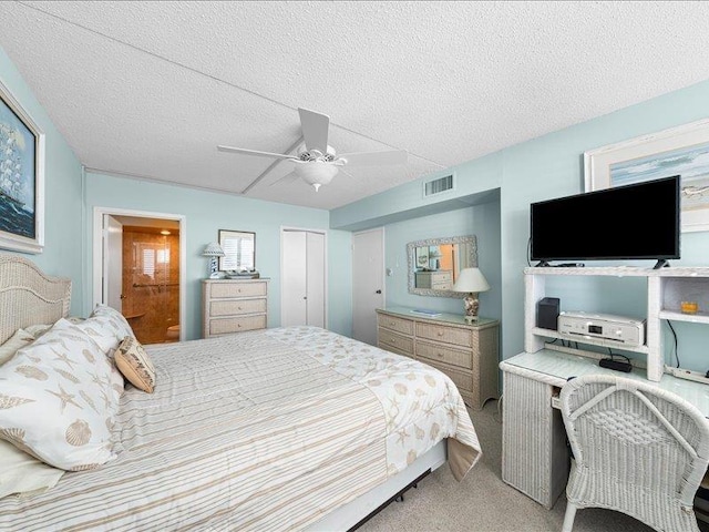 bedroom featuring a closet, light carpet, a textured ceiling, and ceiling fan