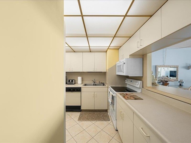 kitchen featuring sink, white appliances, light tile patterned floors, and white cabinets