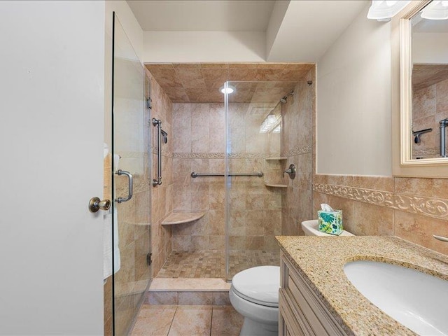 bathroom with tile patterned flooring, toilet, vanity, tile walls, and a shower with door