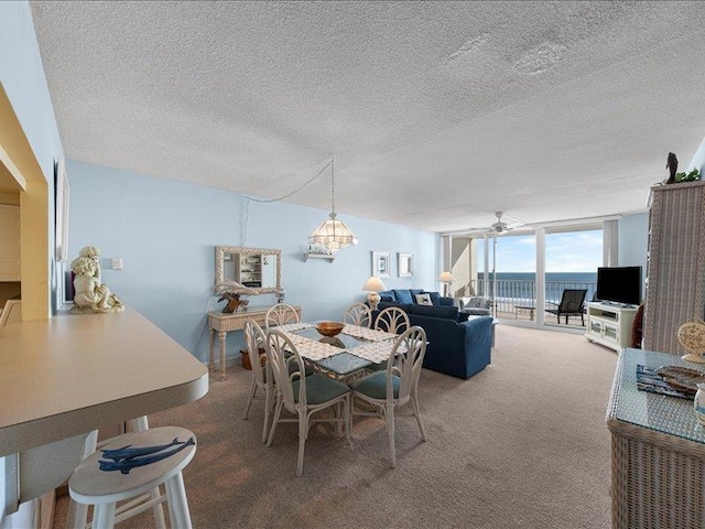 dining room featuring a textured ceiling, a wall of windows, carpet floors, and ceiling fan