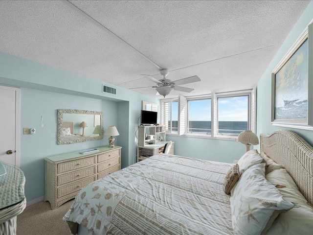 carpeted bedroom with ceiling fan and a textured ceiling