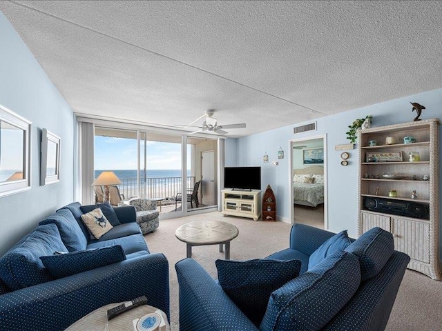 carpeted living room with a textured ceiling and ceiling fan